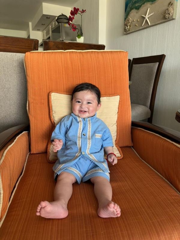 Dionisio bebé, sentado en un sillón y sonriendo con un conjunto azul